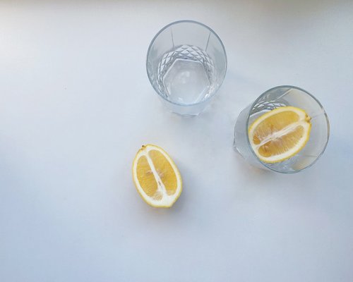 Glass of fresh water with lemon slices on a bright modern desk