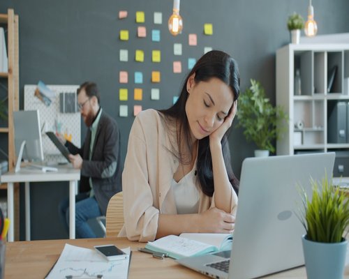 Woman resting her eyes at office desk feeling tired